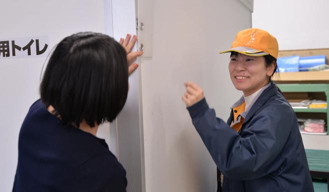 白色に変わったクイックハウスの壁について説明する様子